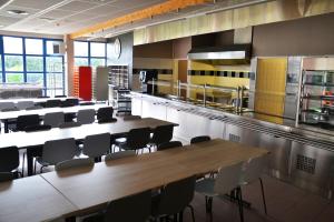 a large room with tables and chairs in a kitchen at Auberge La Digue in Calais