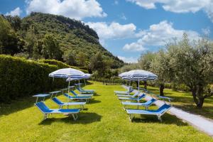 a row of blue lounge chairs with umbrellas at Hotel La Perla - Bike Hotel in Garda