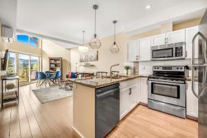 eine Küche mit weißen Schränken und Geräten aus Edelstahl in der Unterkunft Top Floor Apartment at Amenity Rich Resort 406 in West Kelowna