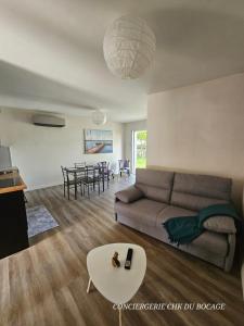 una sala de estar con un sofá y una mesa en Le Petit Ecureuil charmant gîte jardin terrasse, en Les Herbiers