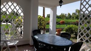 a table and chairs on a porch with a fence at Deiana's Apartment - Cardedu Beachside in Cardedu