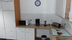 a kitchen counter with a microwave and a clock on the wall at Haus am Bahndamm in Holzminden +5 photos