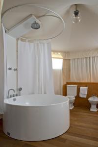 a bathroom with a large white tub and a toilet at HMO Glamping & Suites in Vignanotica in Mattinata +37 photos