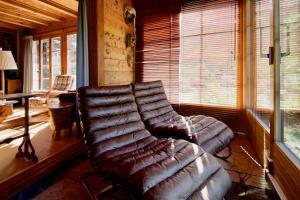 a leather couch in a living room with a window at Magnifique chalet familial pour 10 personnes au coeur de Nax in Nax