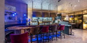 a bar in a restaurant with purple stools at PLAZA Residence Stuttgart-Ditzingen in Ditzingen