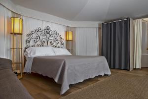 a bedroom with a white bed with a wrought iron headboard at HMO Glamping & Suites in Vignanotica in Mattinata