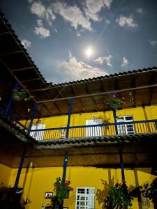 un edificio amarillo con macetas en el balcón en Hospedaje Campestre Araucarias, en Santa Rosa de Cabal