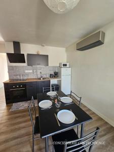 Una cocina con una mesa y sillas negras en una habitación. en Le Petit Ecureuil charmant gîte jardin terrasse, en Les Herbiers 21 fotos más
