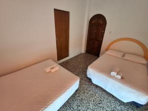 2 camas en una habitación pequeña con sábanas rosas en La Tía, en Jalapa