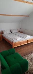 a bedroom with a large bed and a green chair at Къща за гости Сара in Velingrad