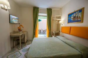 a bedroom with a bed and a desk and a window at Hotel Rivamare in Ischia