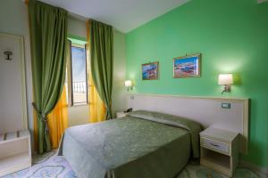 a bedroom with a bed with green walls and a window at Hotel Rivamare in Ischia
