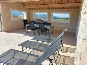 a patio with a table and chairs and windows at La Fenière in Sault-de-Vaucluse