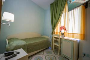 a bedroom with a bed and a desk and a window at Hotel Rivamare in Ischia
