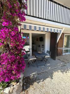 a patio with a table and purple flowers at Studio thalie in Bormes-les-Mimosas
