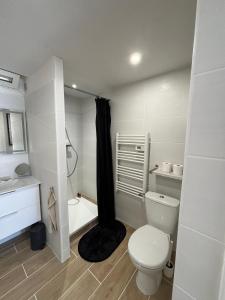 a white bathroom with a toilet and a bath tub at Studio thalie in Bormes-les-Mimosas