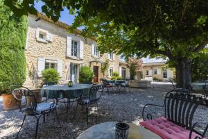 a patio with tables and chairs in front of a building at Chambre d'hôtes - B&B - Le Cocon de Manon en Luberon in Lagnes