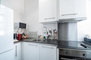 a kitchen with white cabinets and a stainless steel sink at T2 de charme vieux Rennes - Ty ar Vasselot in Rennes