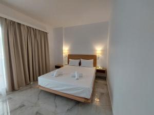 a bedroom with a white bed with two white pillows at Blue Bay Hotel in Iraklitsa