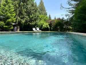 a pool of clear blue water with a white bench at Hotel Xalet del Golf in Puigcerdà