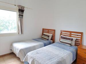 two beds in a room with a window at Comfortable villa near the beach in Jolly Harbour