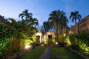ein Haus mit Palmen und Lichtern im Hof in der Unterkunft The Maya Seminyak Villas in Seminyak