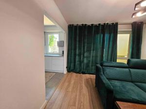 a living room with a green couch and a window at Apartament Kilińskiego in Ełk