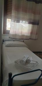 Una cama blanca con toallas y una ventana. en Casa Alice vicino al mare, en Porto Pino