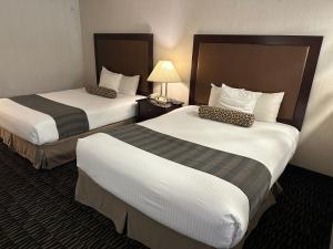 a hotel room with two beds and a lamp at Sojourn Suites Portland Airport in Portland +27 photos