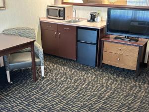 a kitchen with a tv and a desk with a microwave at Sojourn Suites Portland Airport in Portland
