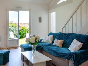 een blauwe bank in een woonkamer met een vaas met bloemen bij Holiday Home Les Pins by Interhome in Pornic
