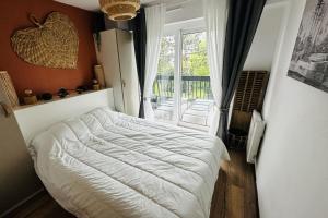 a bedroom with a white bed and a window at Lovely T2 with garden by the sea in Camiers