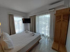 a bedroom with a white bed and a large window at Blue Bay Hotel in Iraklitsa