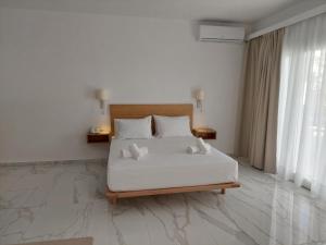 a bedroom with a bed with white sheets and pillows at Blue Bay Hotel in Iraklitsa