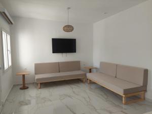 a living room with two benches and a flat screen tv at Blue Bay Hotel in Iraklitsa
