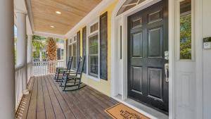 ジョージタウンにあるBeach Retreat home by Peace Vacationsの黒いドアと椅子のある玄関ポーチ