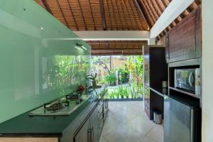 eine Küche mit einer grünen Arbeitsplatte und eine Küche mit einem TV in der Unterkunft The Maya Seminyak Villas in Seminyak