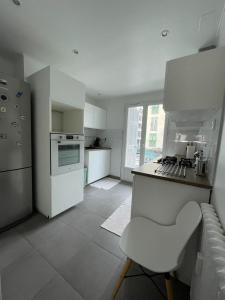 a kitchen with white appliances and a white chair in it at 50m2 Climatisé Proche Mer in Nice