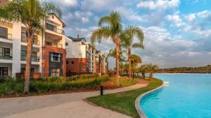 a building with palm trees next to a swimming pool at 521 at The Blyde in Pretoria