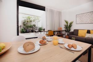 a wooden table with plates of bread and orange juice at Aspasios Atocha Apartments in Madrid