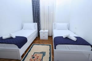 Un dormitorio con dos camas y una alfombra. en The Cozy 2 room apartment Berat, en Berat