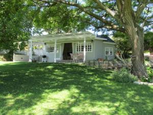 a white house with a tree in the yard at Deja Vu Cottage in Sedgefield