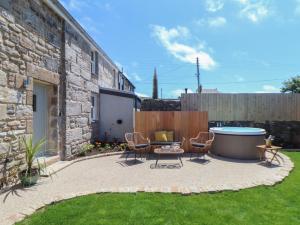a patio with chairs and a hot tub in a yard at Victory View in Penzance