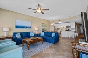 a living room with blue couches and a kitchen at Phoenix 6 Unit 1213 in Orange Beach