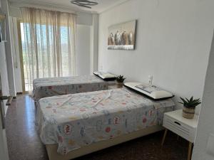 a bedroom with two beds and a window at Euromar Playa Cullera frente al mar con garaje in Cullera