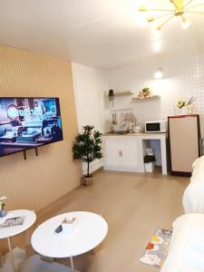 a living room with two tables and a tv on the wall at NK hostel 18 in Thung Si Kan