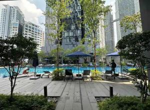 Una piscina con sillas y sombrillas en una ciudad. en Star Resident KLCC By M&T, en Kuala Lumpur