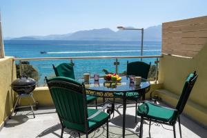a table and chairs on a balcony with a view of the ocean at Sunlit & Sunny Rose Villas in Agios Nikolaos