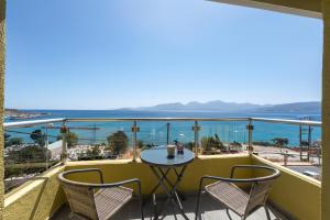 a balcony with a table and chairs and the ocean at Sunlit & Sunny Rose Villas in Agios Nikolaos
