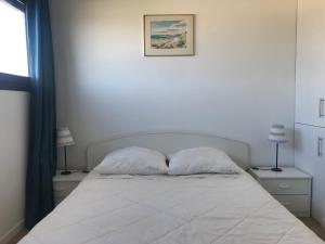 un letto bianco con due cuscini in una camera da letto di LACANAU Océan a Lacanau